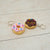 Two donut-shaped keychains with sprinkles on a light wooden surface