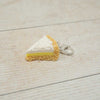 Keychain shaped like a slice of pie on a light wooden surface