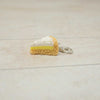 Miniature keychain of a slice of cake on a light wooden surface