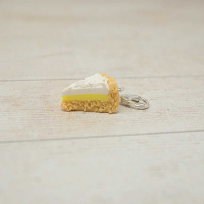 Miniature keychain of a slice of cake on a light wooden surface