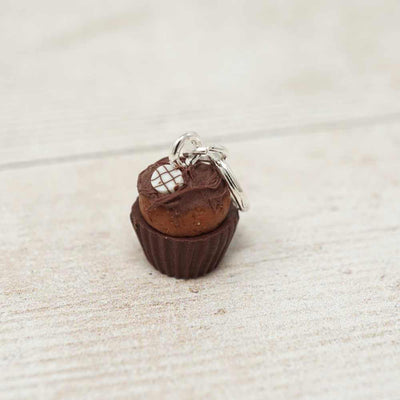 Small keychain shaped like a chocolate cupcake with a brown top on a light beige surface.