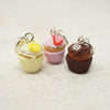 Three cupcake-shaped keychains on a textured surface