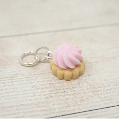 Keychain with a pink cream puff on a light wooden surface