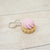 Keychain with a pink cream puff on a light wooden surface