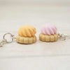 Two small keychains shaped like ice cream cones with pink and yellow tops on a white background.