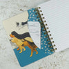 Notebook with dog illustrations on a textured surface showing an inside pocket | Yarn Worx