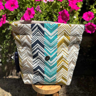 Patterned bag with a button on a wooden stool against a background of pink flowers.