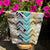 Patterned bag with a button on a wooden stool against a background of pink flowers.
