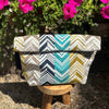 Folded fabric Project bag with chevron pattern on a wooden stool with flowers in the background