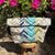 Folded fabric Project bag with chevron pattern on a wooden stool with flowers in the background