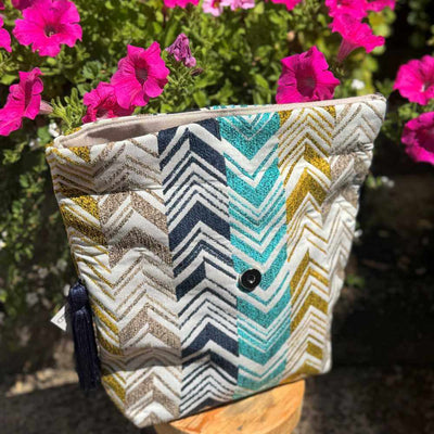 Fabric pouch with chevron pattern in front of pink flowers