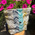 Fabric pouch with chevron pattern in front of pink flowers