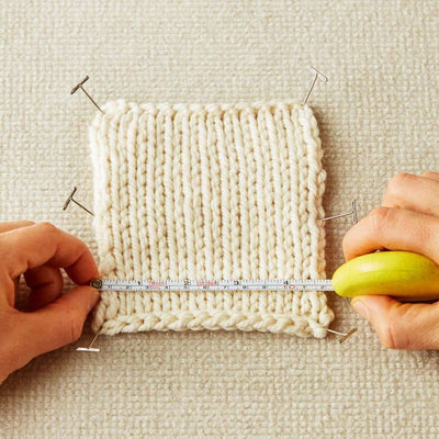 Cocoknits - Tape Measure - photo shows person measuring a knitted tension square using the Mustard Seed coloured tape measure | Yarn Worx