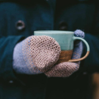 The Crochet Project - Crochet Yeah! person wearing mittens holding a mug of hot drink | Yarn Worx
